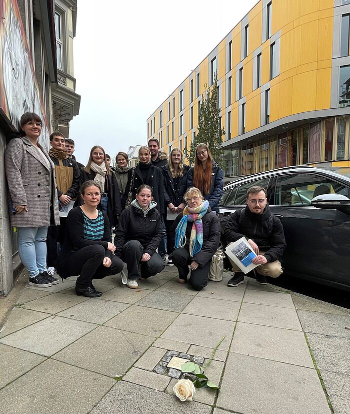 Mehrere Personen sitzen vor gereinigten Stolpersteinen.