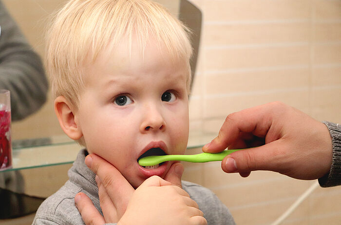 Zweijährigem Kleinkind werden die Zähne geputzt