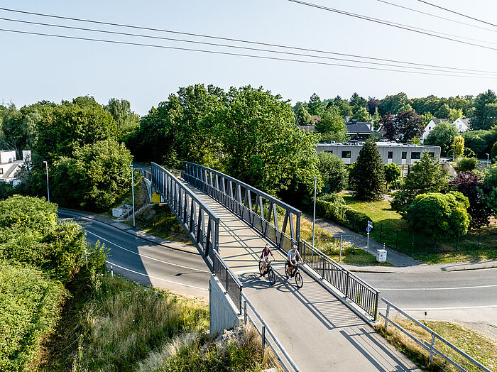 Zwei Radfahrer fahren über eine Brücke.