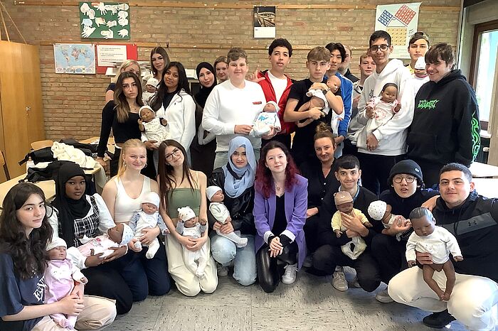 Schüler und Schülerinnen mit Puppen, die echte Babys simulieren.