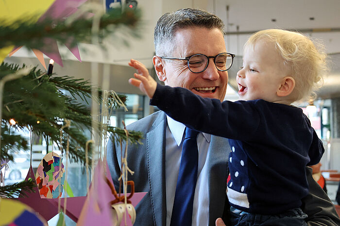 „Nach ganz oben soll der Stern!“ – Städteregionsrat Dr. Tim Grüttemeier hilft den Kindern, die Äste zu erreichen, die weit oben sind.  