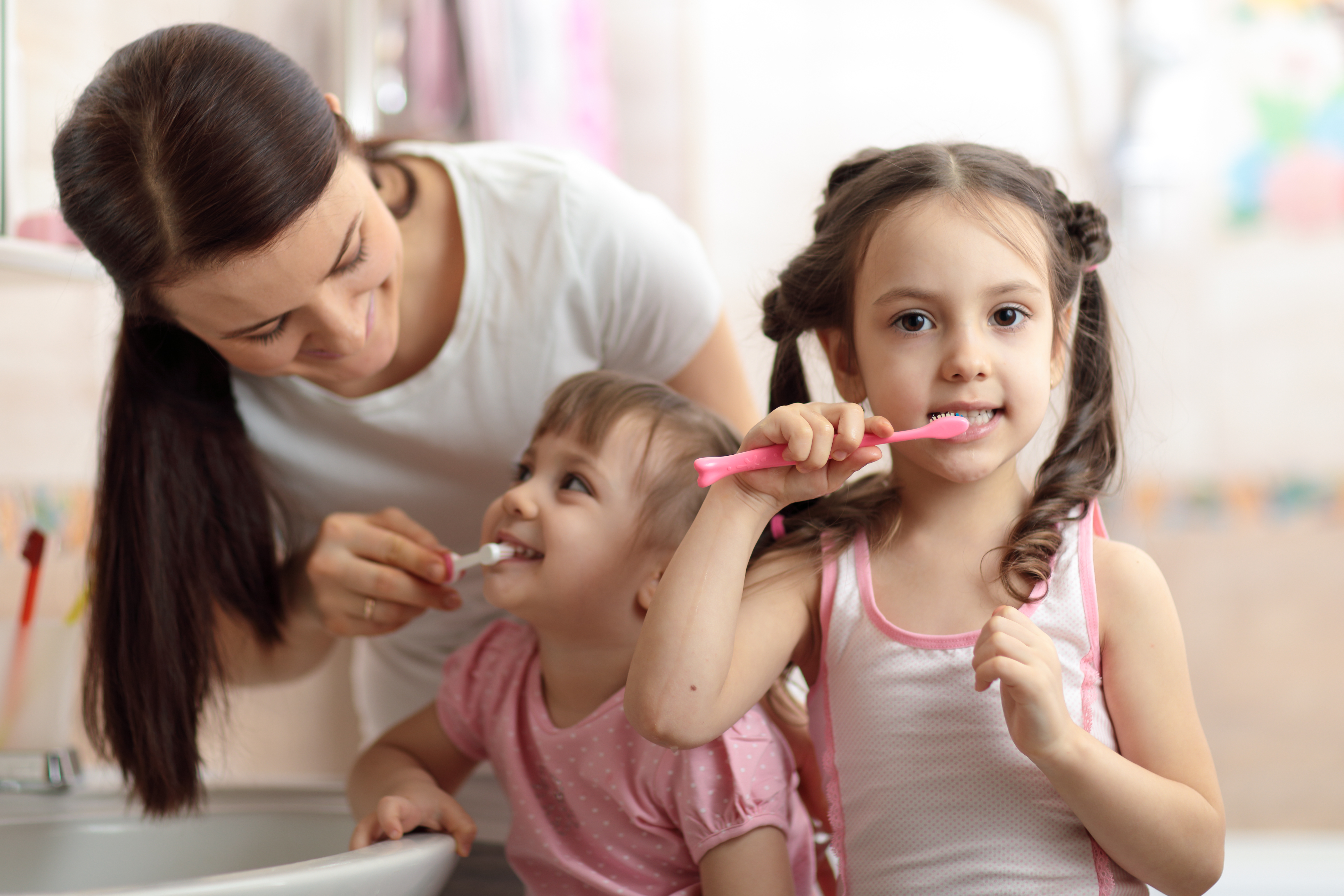 Mutter und Kinder putzen Zähne