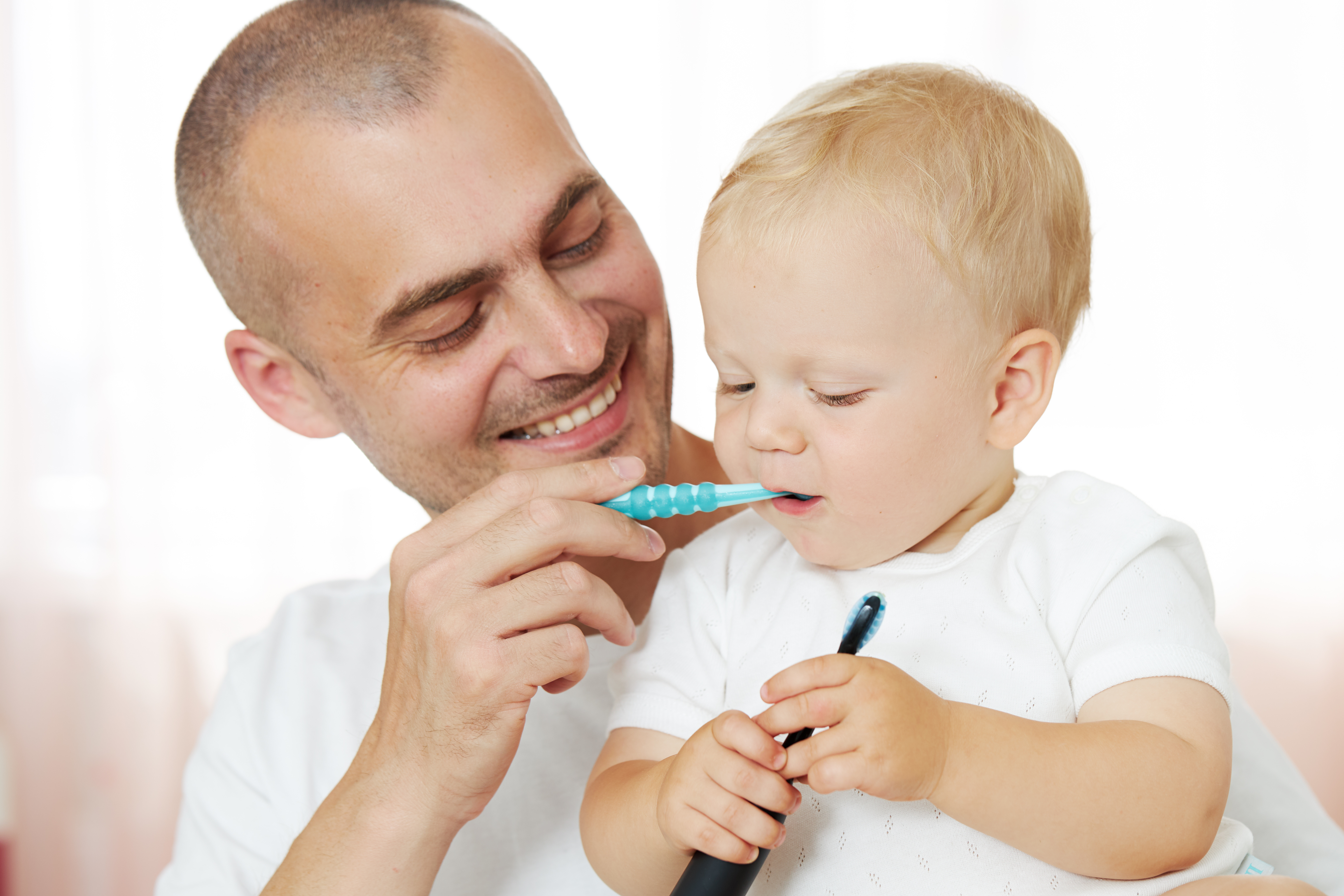 Vater putzt einjährigem Baby die Zähne.