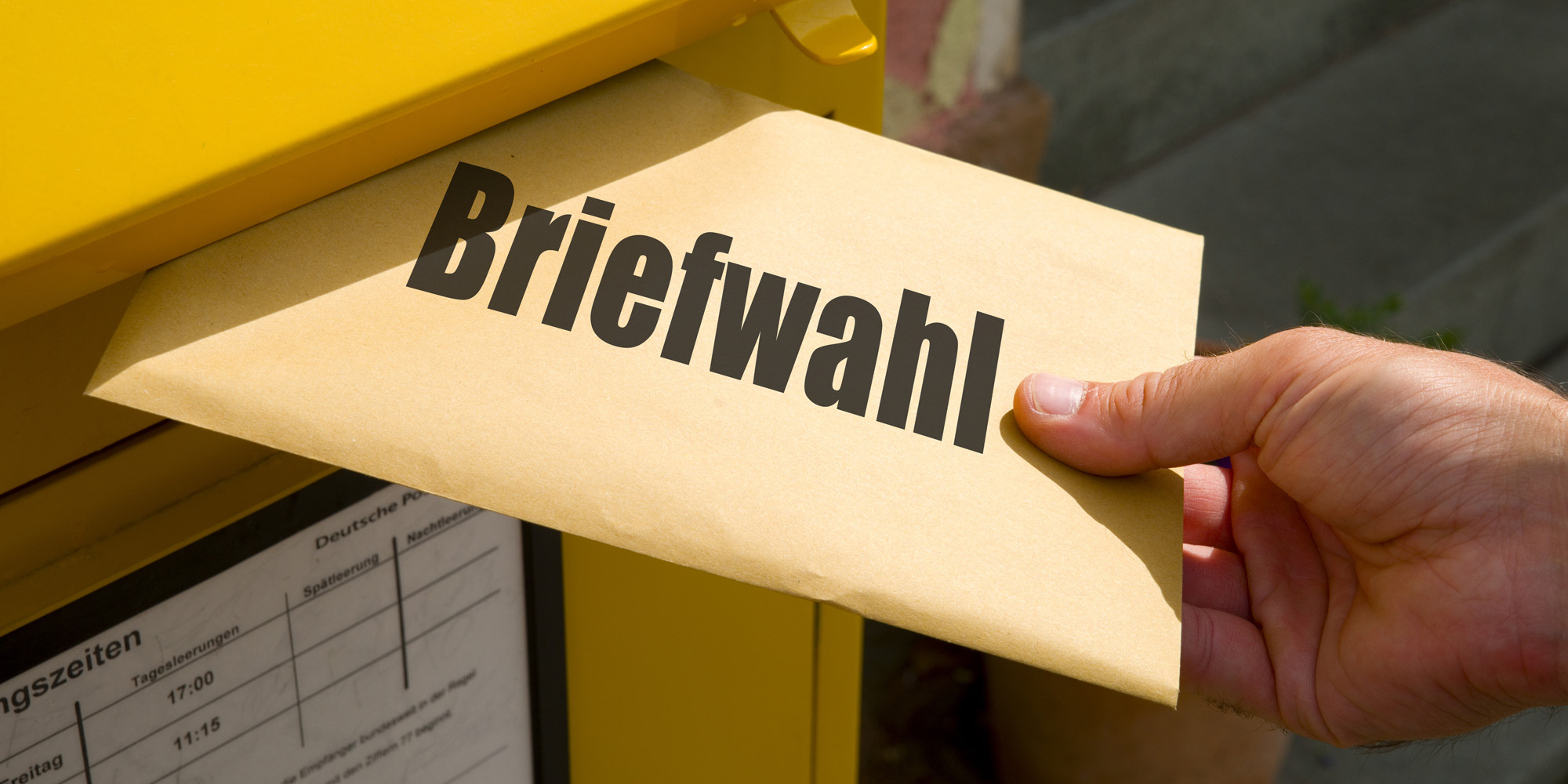 Einwurf von Briefwahlunterlagen in einen Briefkasten.