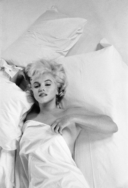 Die Schauspielerin Marilyn Monroe räkelt sich auf einem Bett