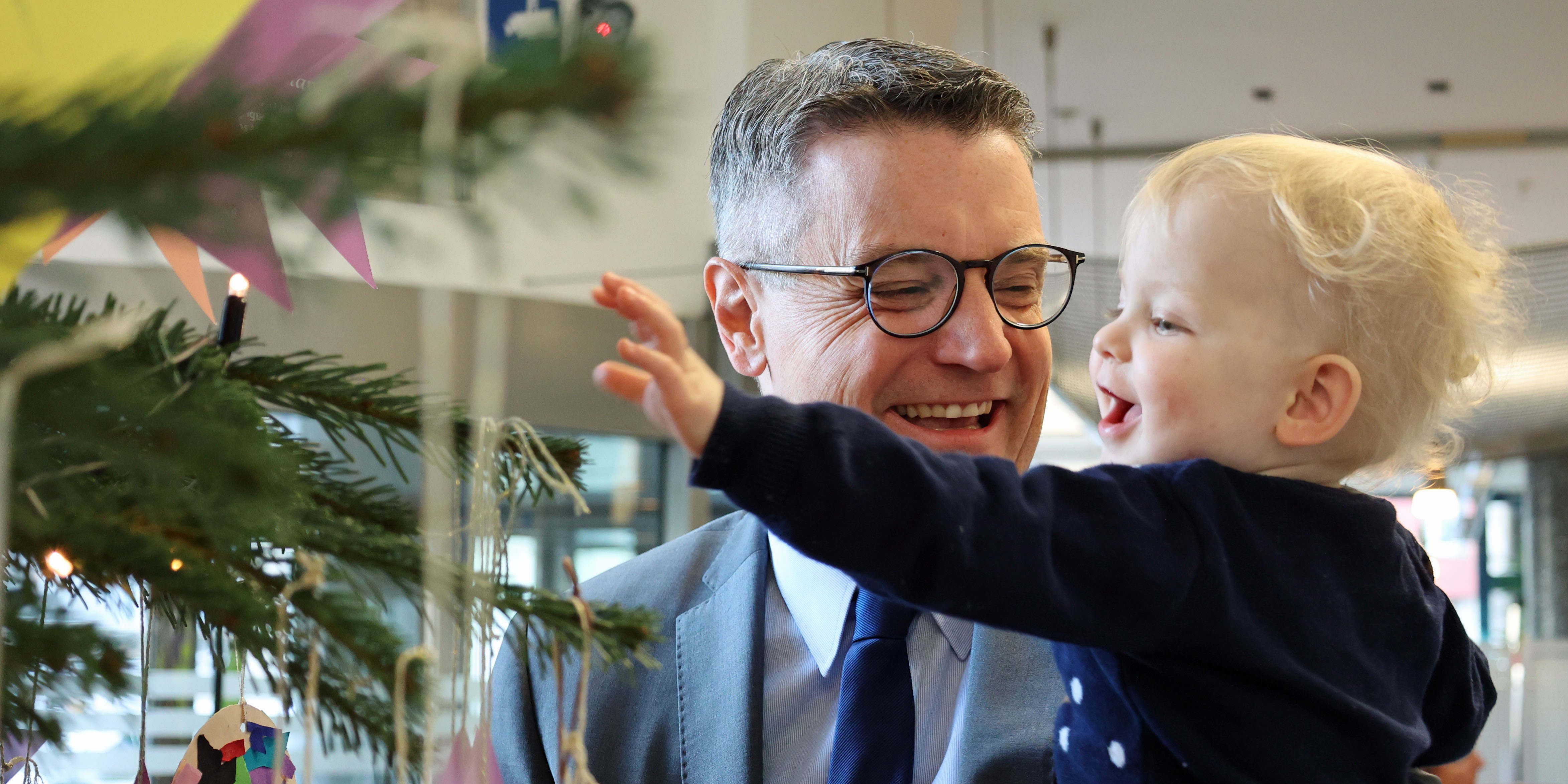 Dr. Grüttemeier schmückt mit Kitakindern den Wunschbaum.